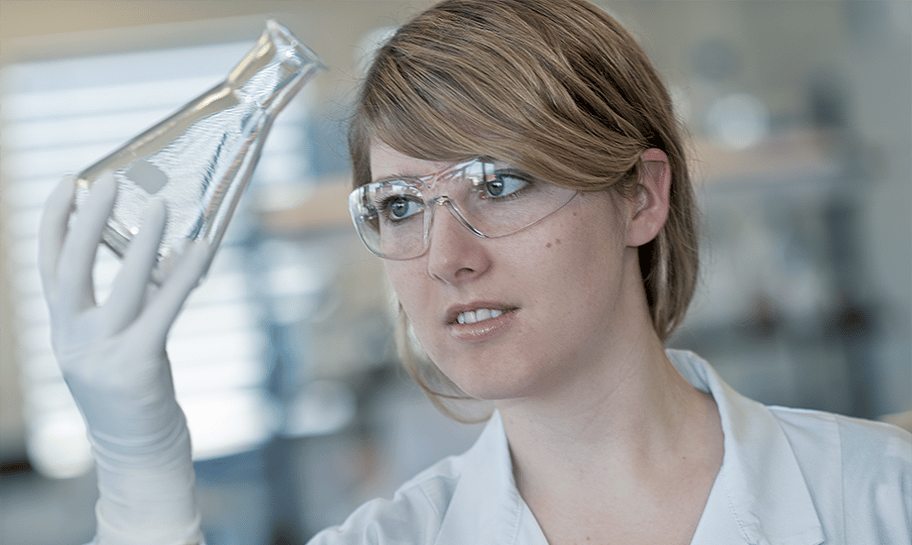 Eine Labormitarbeiterin prüft ein gereinigtes Laborglas