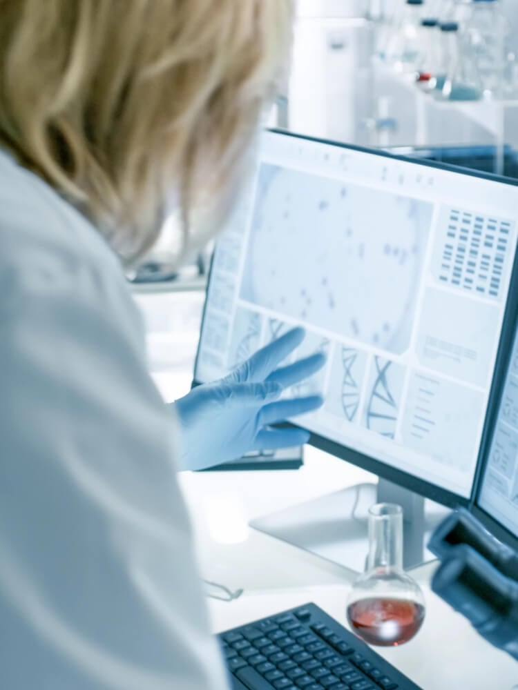 Lab technician analysing process data on a PC screen