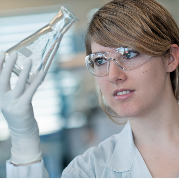 Chemical laboratory assistant checks cleanliness of laboratory glassware